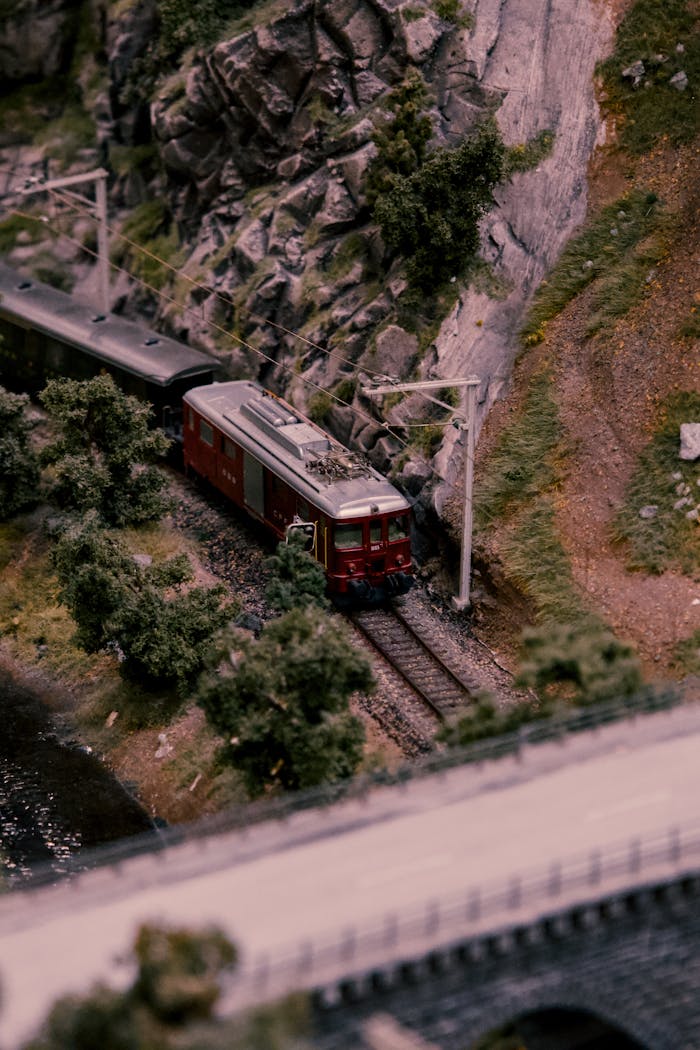 Detailed miniature train model traversing a scenic model landscape with rocks and vegetation.